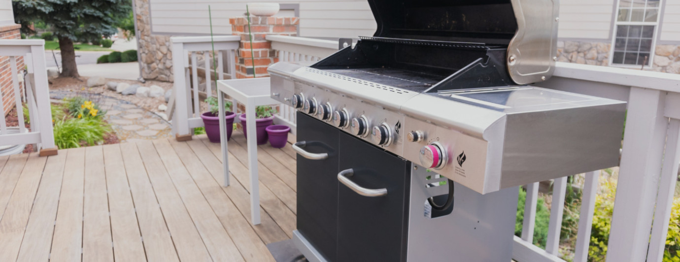 grill gazowy ustawiony w ogrodzie na zielonej trawie z grillującymi się potrawami