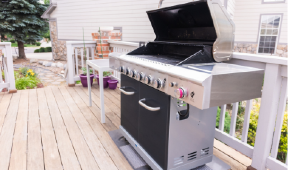 grill gazowy ustawiony w ogrodzie na zielonej trawie z grillującymi się potrawami