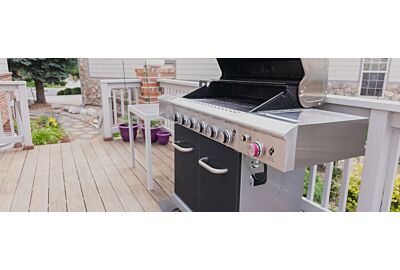 grill gazowy ustawiony w ogrodzie na zielonej trawie z grillującymi się potrawami