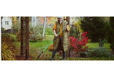 kobieta grabiąca liście w ogrodzie jesienią