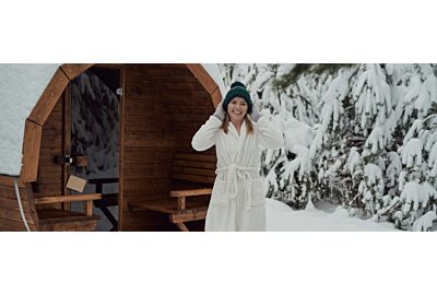 kobieta stojąca w białym szlafroku przed sauną ogrodową