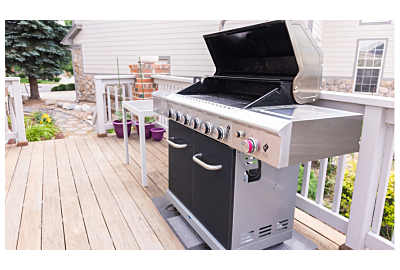 grill gazowy ustawiony w ogrodzie na zielonej trawie z grillującymi się potrawami