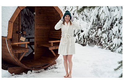 kobieta stojąca w białym szlafroku przed sauną ogrodową 