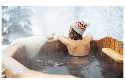 kobieta mieszajaca gorącą wode w bali ogorodowej ustawionej w osniezonym ogrodzie przy lesie