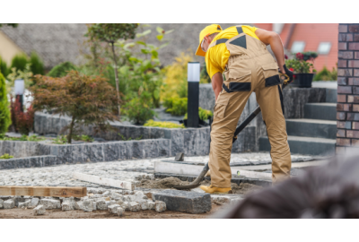 robotnik układający kostkę brukową w ogrodzie