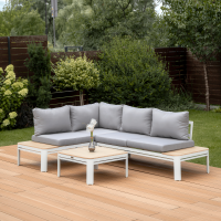 Narożna sofa ogrodowa Raymond White z szarymi poduszkami na aluminiowej ramie, ustawiona na tarasie z deską kompozytową, obok stolika z drewnianym blatem i wazonem.