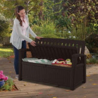 Kobieta otwierająca ławkę ogrodową ze schowkiem, wypełnionym poduszkami i akcesoriami.