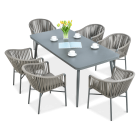 Zestaw nowoczesnych mebli ogrodowych z prostokątnym stołem w grafitowym kolorze i sześcioma fotelami z plecionym oparciem, dekorowany wazonem z żółtymi tulipanami i filiżankami.