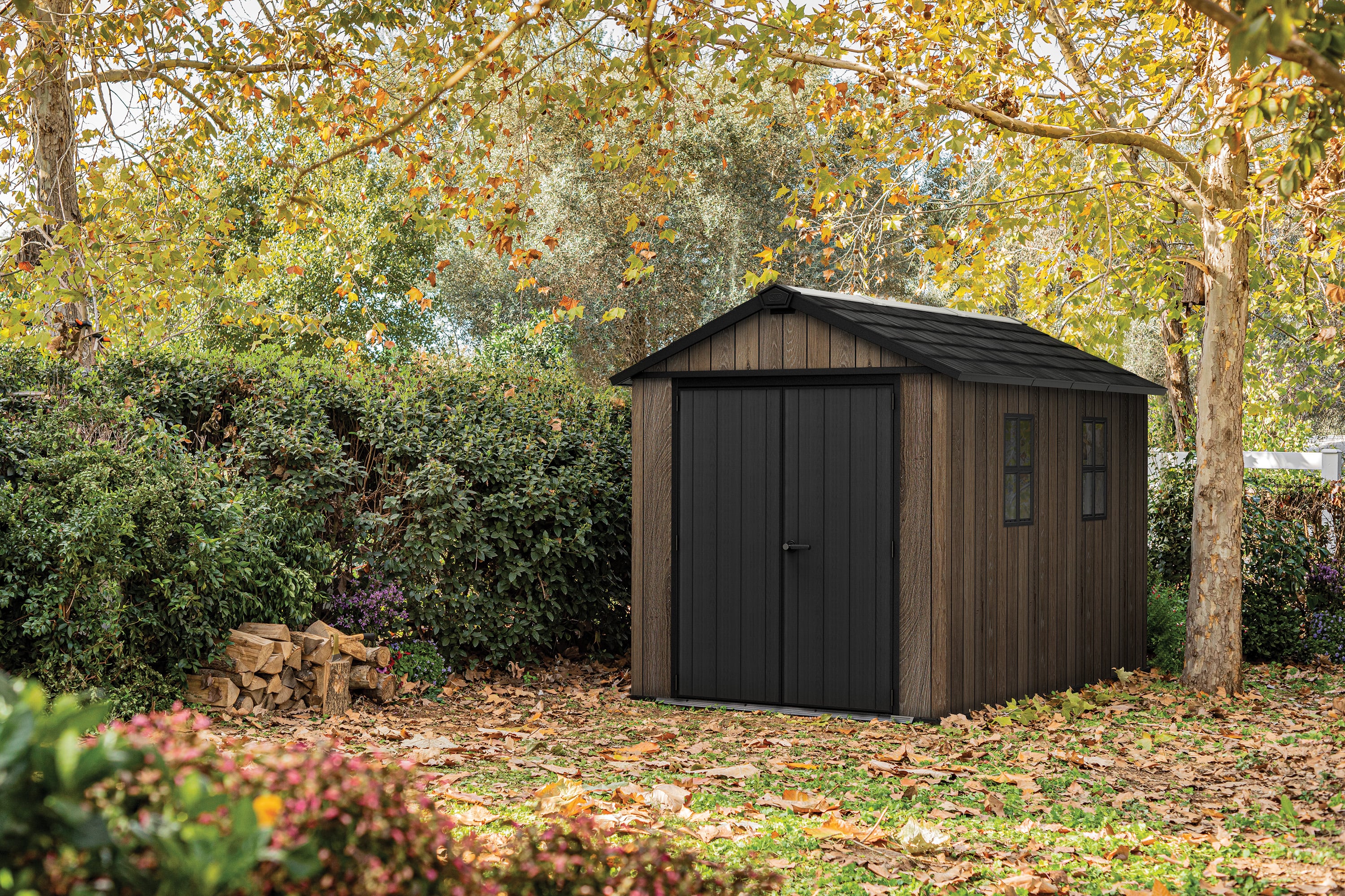 Domek na narzędzia Keter Deco Apex walnut z podw&oacute;jnymi drzwiami i oknami w rustykalnej aranżacji