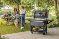 Aranżacja barku w ogrodzie, a w tle rodzina jedząca posiłek