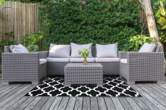 Czarno biały dywan z geometrycznym wzorem na tarasie przy zestawie mebli ogrodowych