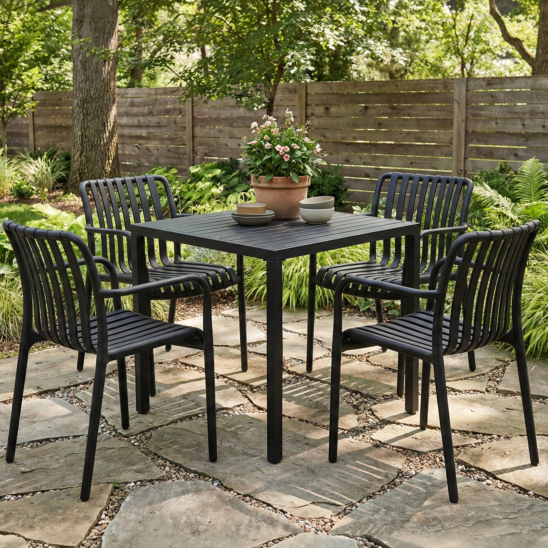 Czarny zestaw mebli ogrodowych z kwadratowym stołem i czterema krzesłami na kamiennym tarasie