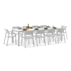 Duży, biały zestaw mebli ogrodowych na jasnoszarym tle. Składa się z prostokątnego, rozkładanego stołu oraz ośmiu krzeseł z podłokietnikami i gładkimi oparciami. Na stole nakryto do obiadu, z widocznymi talerzami, miseczkami, butelką oliwy i kieliszkami.