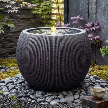 Fontanna ogrodowa grafitowa kulista w eleganckiej aranżacji strefy relaksu z kamieniami i zielenią