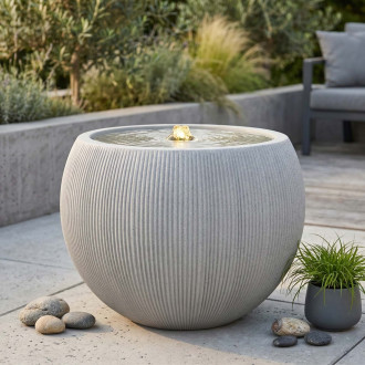 Fontanna ogrodowa kulista jasna w aranżacji ogrodowej przy strefie wypoczynkowej