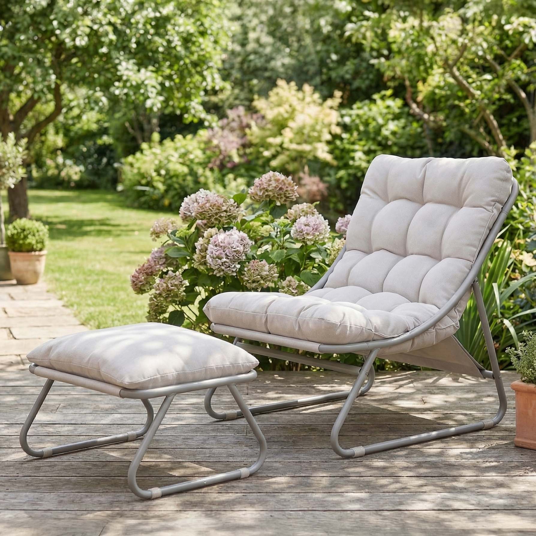 Fotel ogrodowy z podnóżkiem w kolorze szaro beżowym na tarasie w ogrodzie