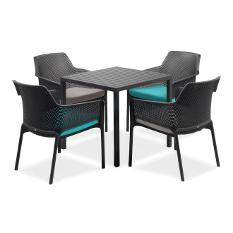 Zestaw mebli ogrodowych w kolorze czarnym na jasnoszarym tle. Składa się z kwadratowego stołu z lamelowym blatem oraz czterech krzeseł z ażurowymi oparciami i podłokietnikami. Na krzesłach leżą poduszki w kolorze turkusowym i szarym. To idealne meble jada