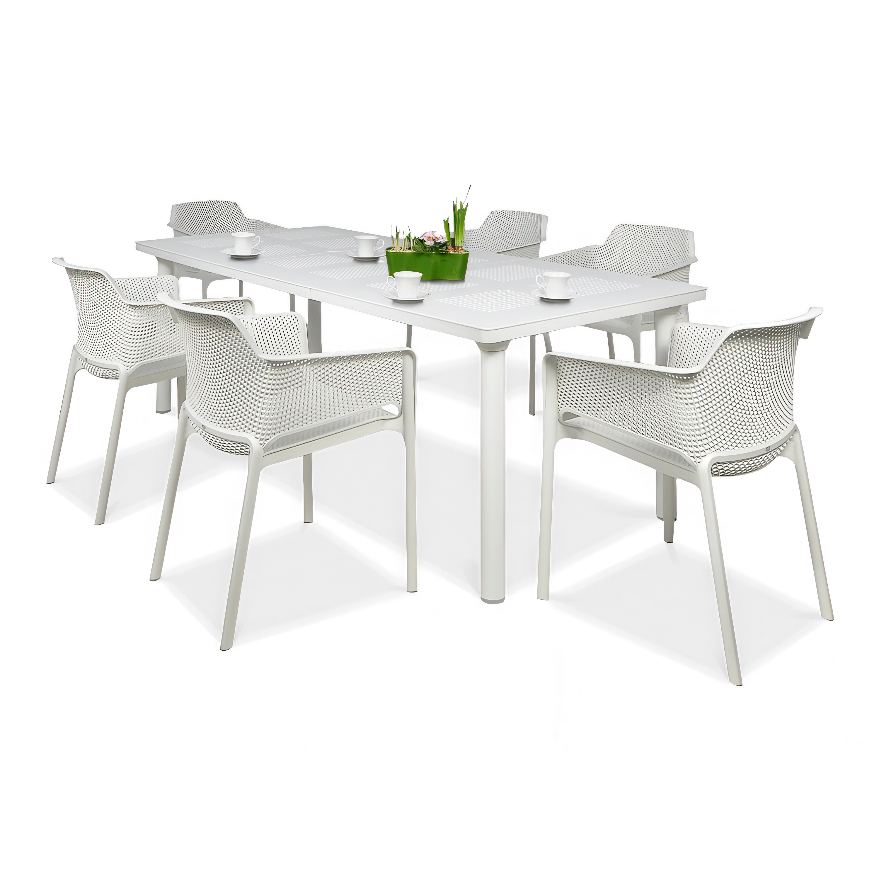 Stół jadalniany i sześć krzeseł w kolorze białym na jednolitym, jasnoszarym tle. Blat rozkładanego stołu ma perforowane wzory, a krzesła mają ażurowe oparcia i siedziska, przypominające plecionkę. Na blacie stołu stoi mała, zielona roślina w doniczce i bi