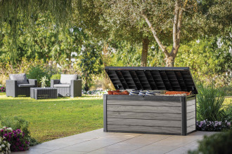 Otwarta skrzynia ogrodowa ustawiona na tarasie przy meblach technorattanowych.