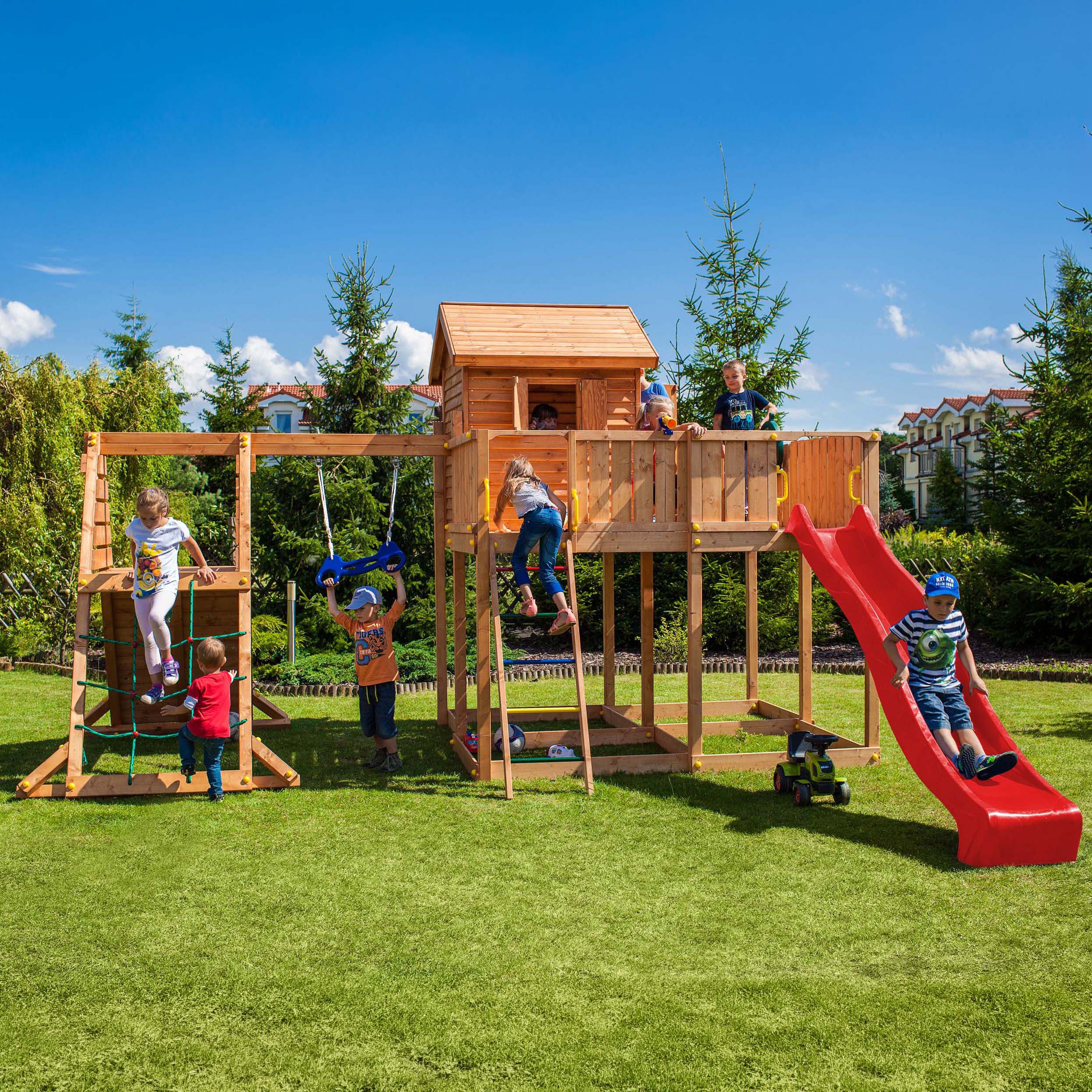 Dzieci bawiące się w ogrodzie na drewnianym placu zabaw