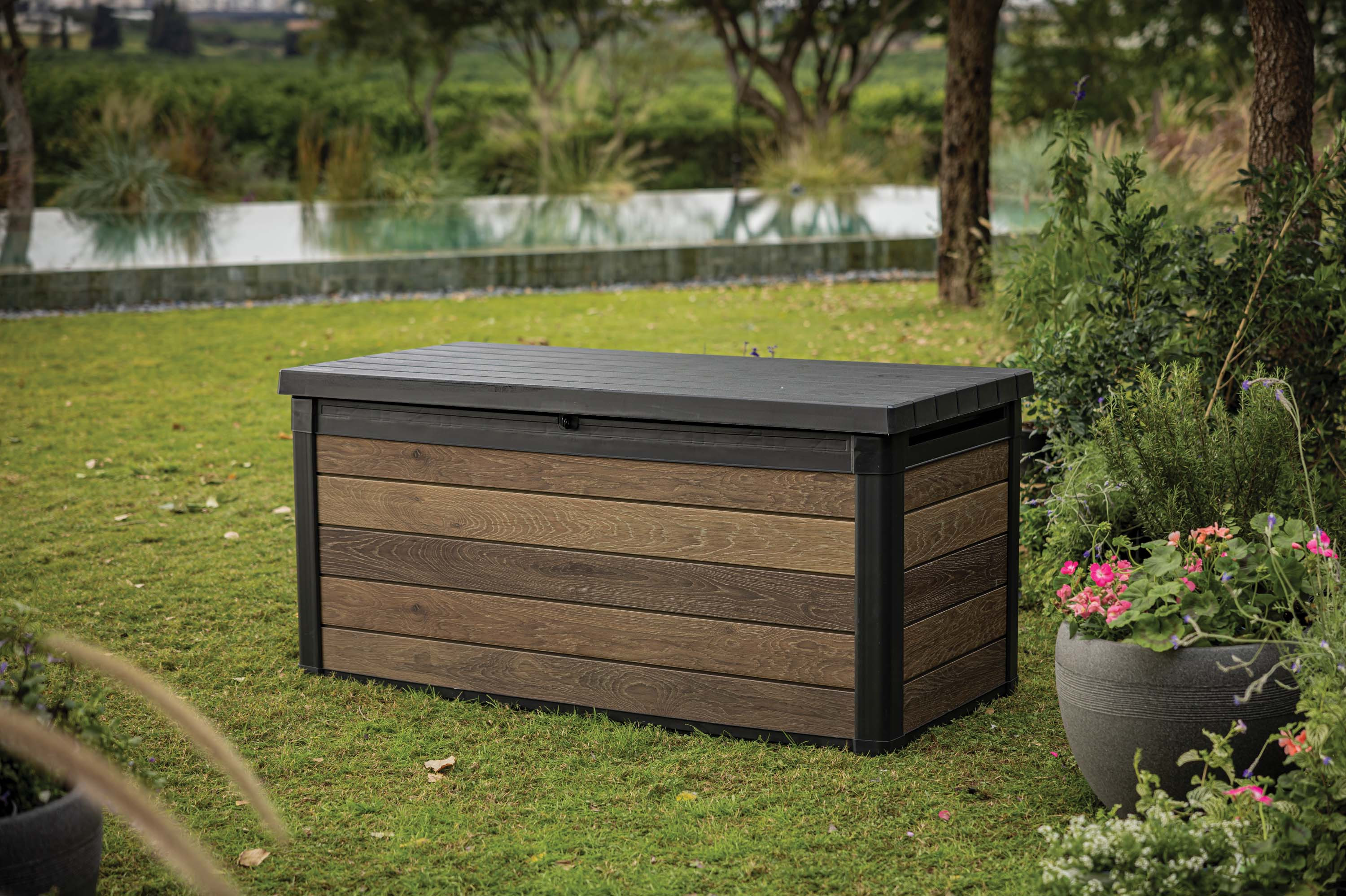 Zamknięta skrzynia ogrodowa na trawniku obok donic z kwiatami i basenu