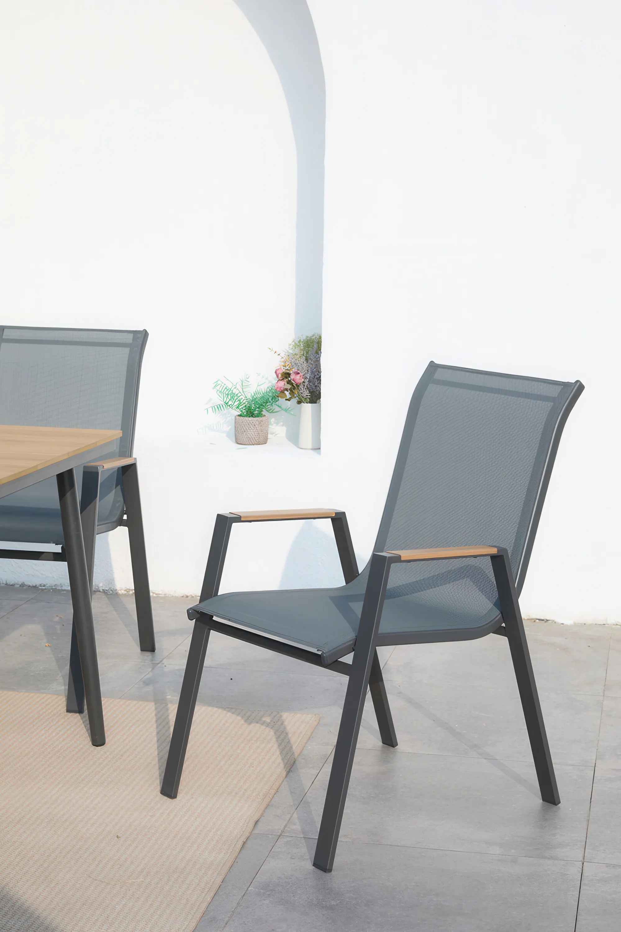 Krzesło do zestawu jadalnianego NOVA DINING 6+1 Dark Grey w aranżacji na tarasie, biała ściana w tle