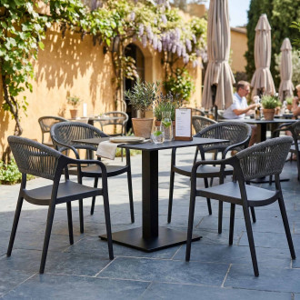 Zestaw mebli ogrodowych czarny stół i cztery krzesła z plecionką aranżacja na tarasie restauracyjnym