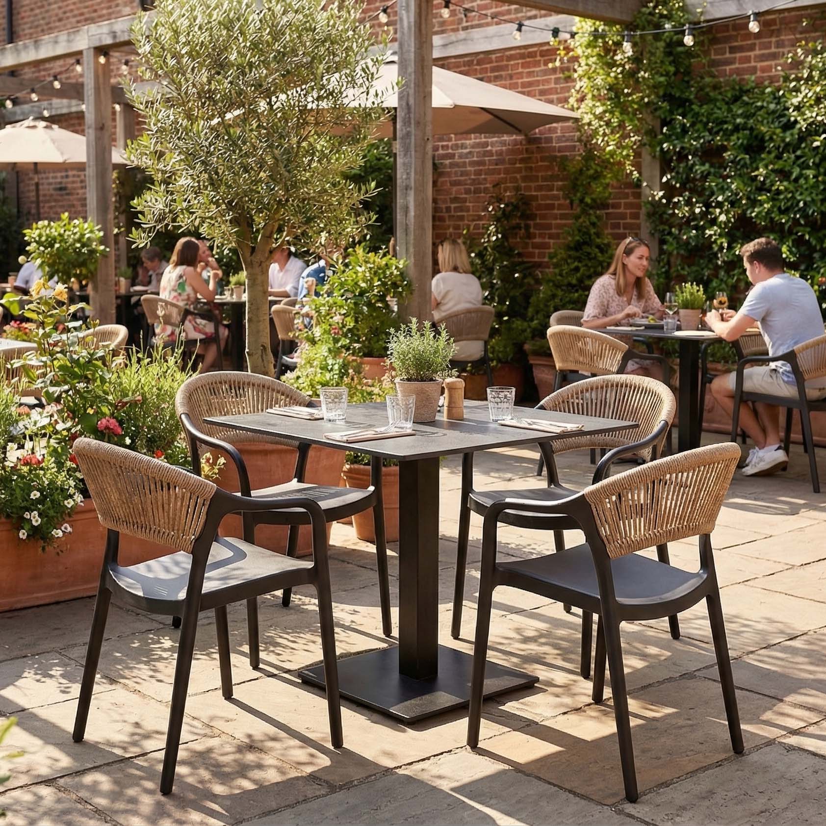 Zestaw mebli ogrodowych czarny stół i krzesła z beżową plecionką aranżacja na patio restauracyjnym