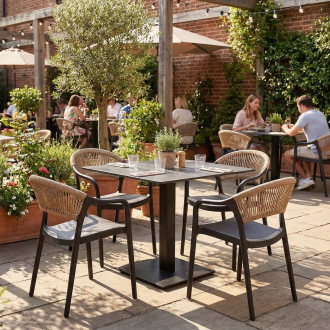 Zestaw mebli ogrodowych czarny stół i krzesła z beżową plecionką aranżacja na patio restauracyjnym