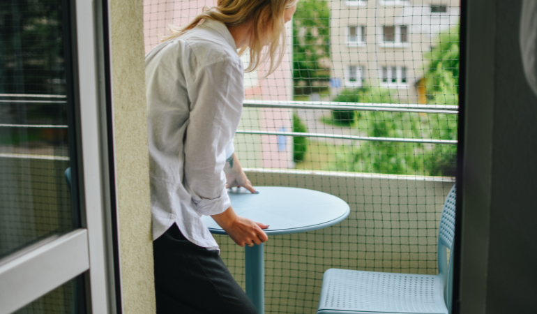 kobieta ustawiająca stolik kawowy na balkonie 