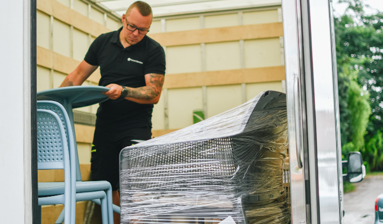 mężczyzna rozładowujący meble z busa 