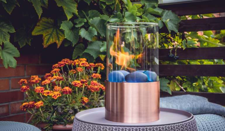 biokominek na tarsie ustawiony na stole ogrodowym 