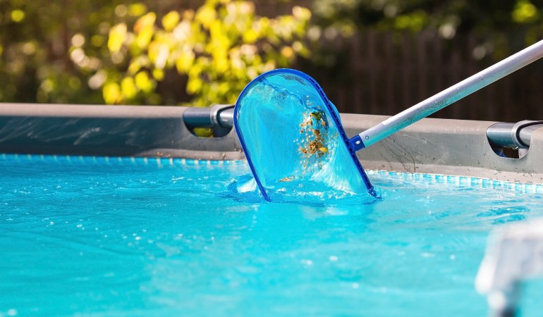 wybieranie podbierakiem liści z basenu ogrodowego 