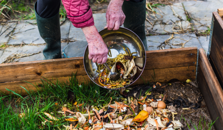 ogrodnik wyrzucający bioodpady do kompostownika otwartego 
