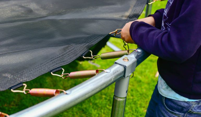 meżczyzna wymieniający sprężyny w trampolinie