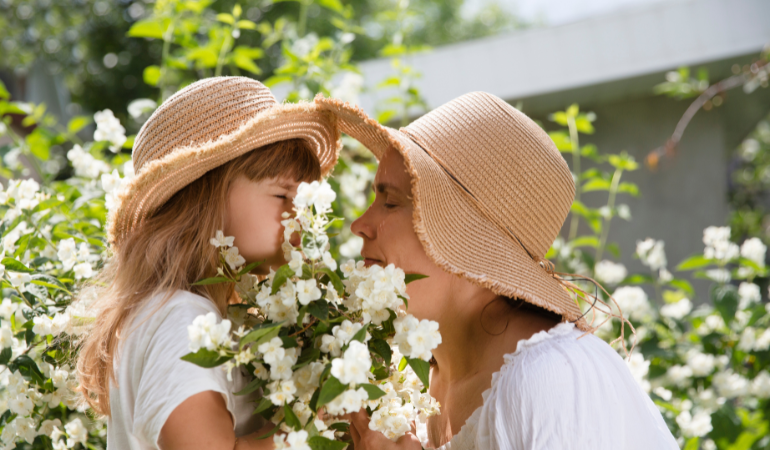 kobieta wąchająca z c&oacute;rką jaśmin w ogordzie 