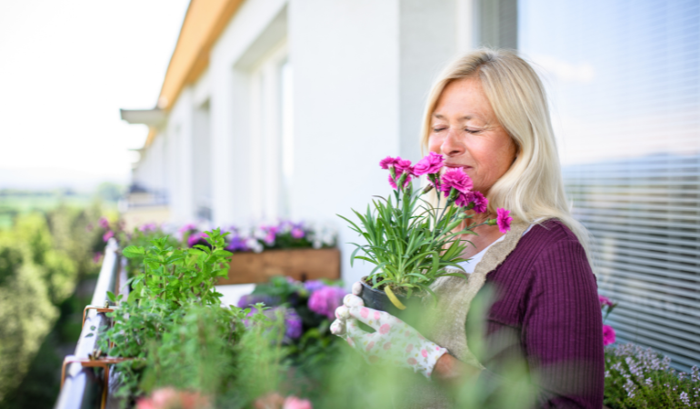 kobieta wąchająca kwiaty na balkonie 