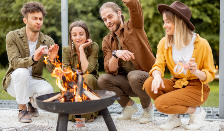 grupa przyjaci&oacute;ł spędzająca czas przy palenisku ogrodowym 