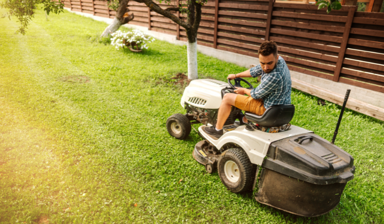 mężczyzna koszący traktorkiem koszącym trawnik w ogrodzie 