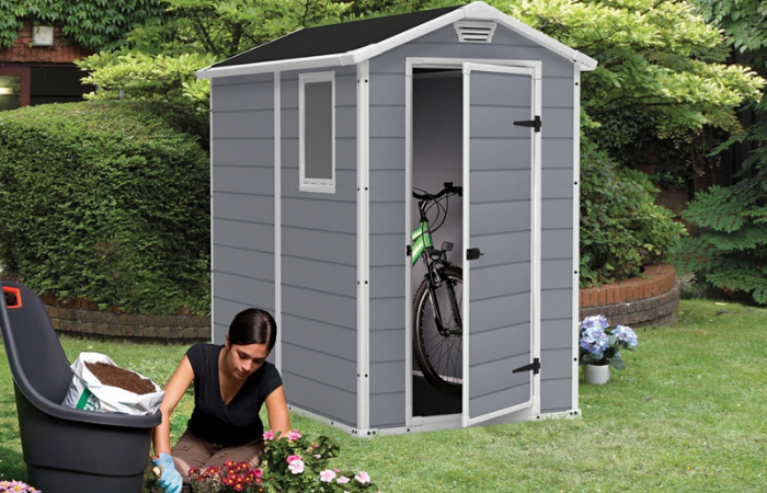 domek narzędziowy z tworzywa sztucznego w kolorze szarym ustawiony na ogr&oacute;dkach działkowych 