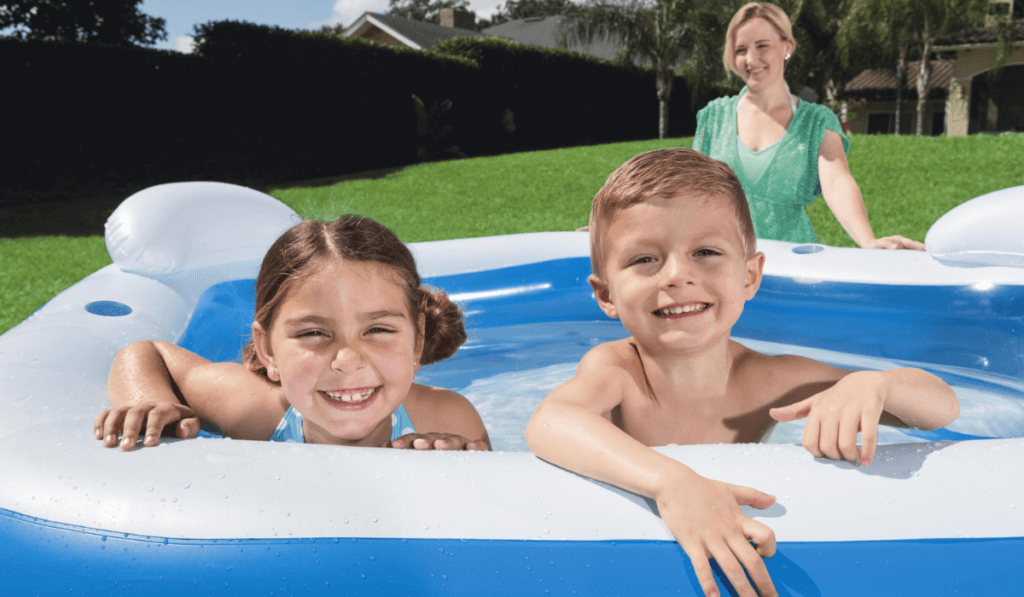 Dzieci w basenie dmuchanym przy pilnującej ich matce