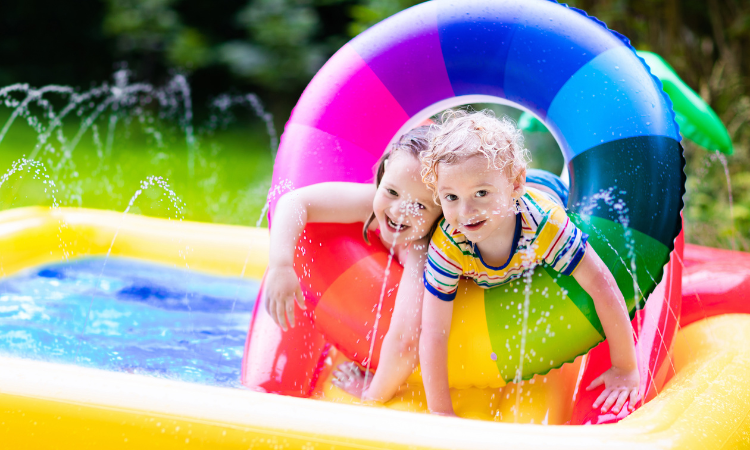Dzieci bawiące się w nadmuchiwanym basenie dla dzieci. Dzieci pływają i pluskają się w kolorowym ogrodowym centrum zabaw. Szczęśliwy chłopiec i dziewczynka bawią się zabawkami wodnymi w upalny letni dzień. 