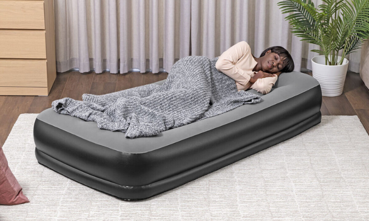 kobieta śpiąca w salonie pod kocem na materacu dmuchanym