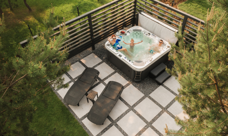 Widok z góry na rodzinę relaksującą się w wannie z hydromasażem na świeżym powietrzu latem.