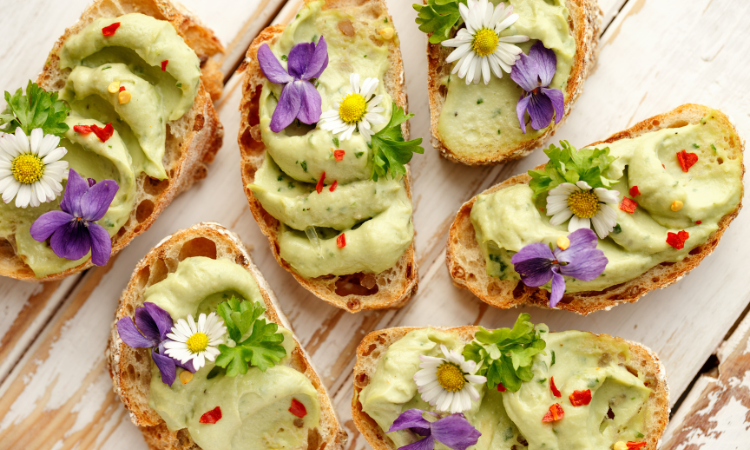 pięknie przystroje kwiatami jadalnymi kanapki z zielona pastą