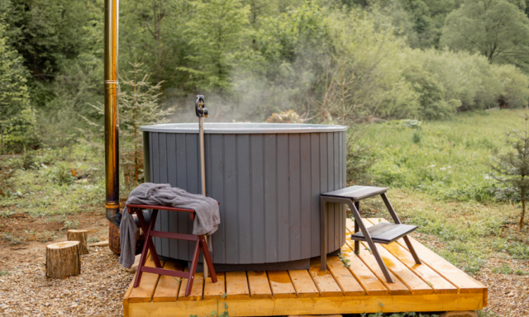balia z gorącą wodą ustawiona w ogrodzie z widokiem na las i góry