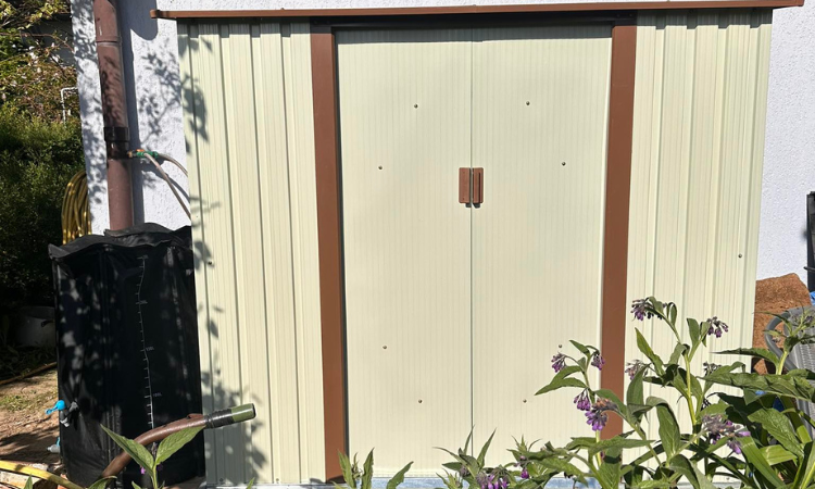 domek ogrodowy ustawiony pod ścianą domu jednorodzinnego