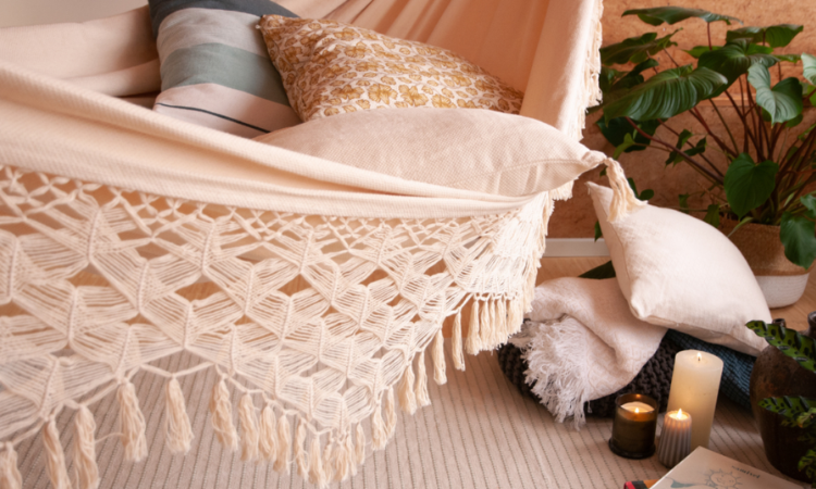 beżowy hamak z frędzlami z dodatkami takimi jak kolorwoe poduszki i koce