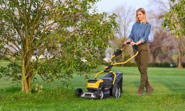 kobieta kosząca trawę w ogrodzie 