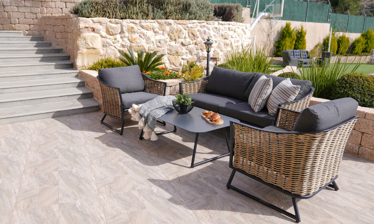 meble ogrodowe z rattanu sofa dwa fotele i stoik z szarymi grubymi poduchami 